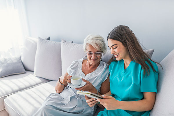 Happy patient is holding caregiver for a hand while spending time together.